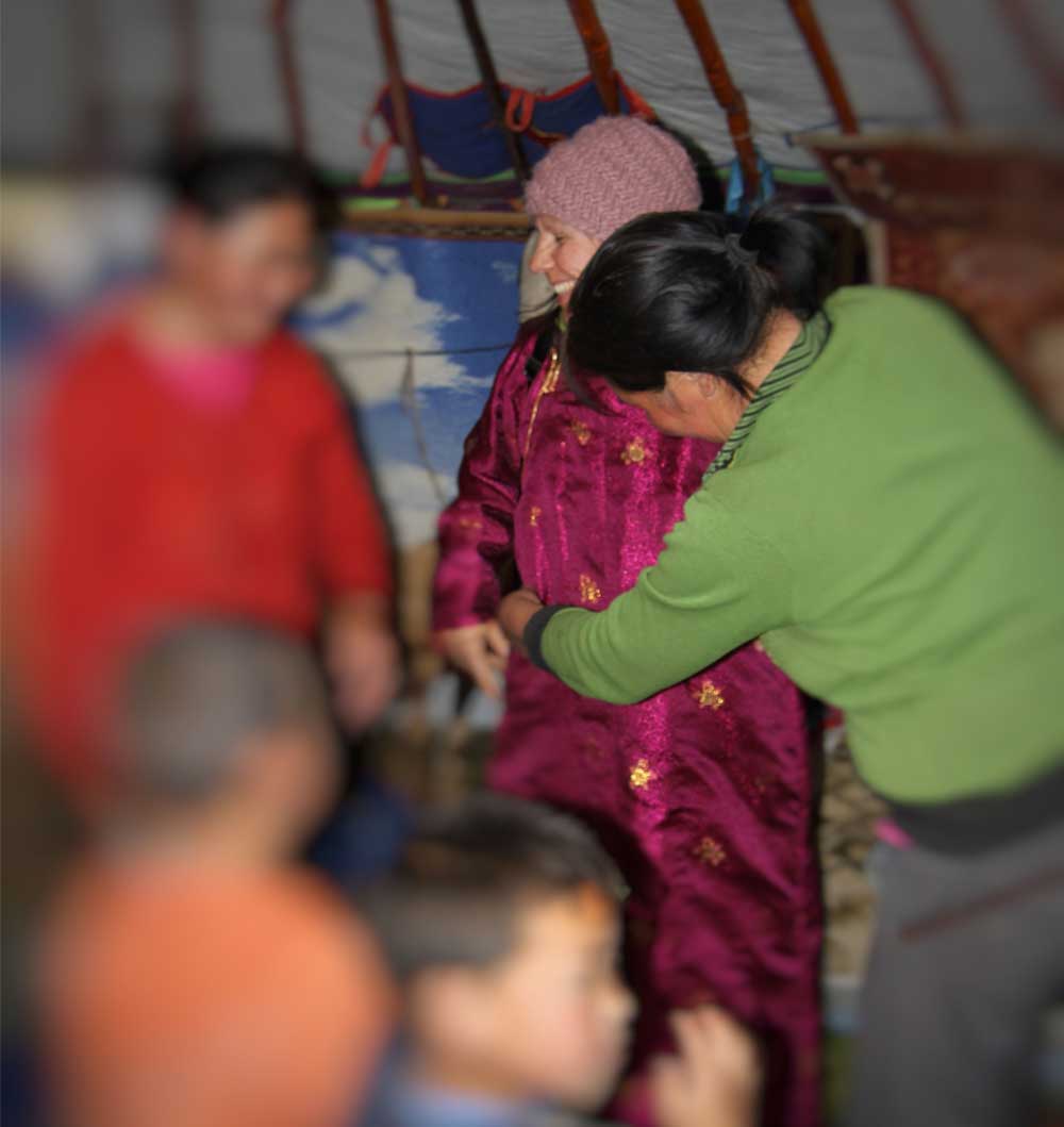 Energietherapeutin Manuela Krah zu Gast im Zelt bei einem Naturvolk in der Mongolei. Sie probiert ihren neuen, fuchsiaroten Mantel an, den sie bei den Gastgebern gekauft hat.