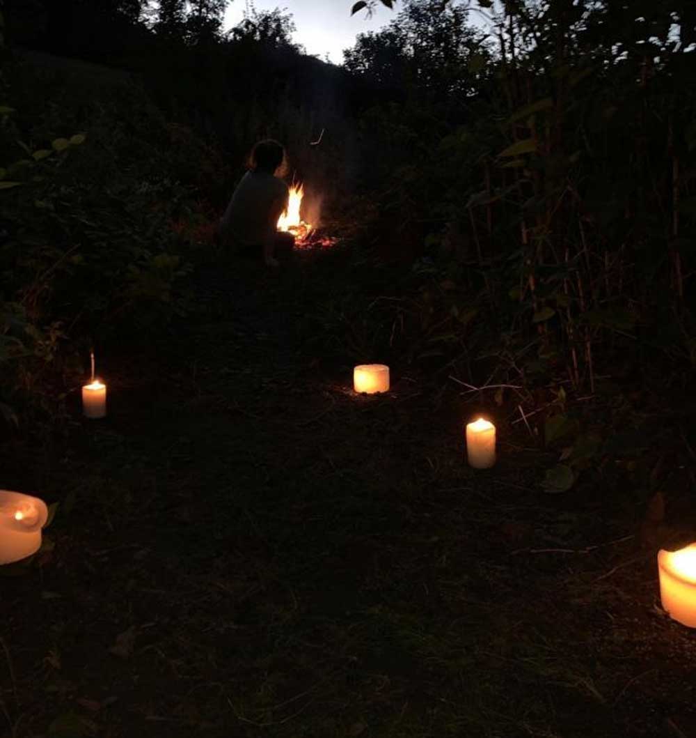 Schwitzhütte in der Dunkelheit. man sieht nur das Kerzenlicht auf dem Weg zur Schutzhütte im Wald.